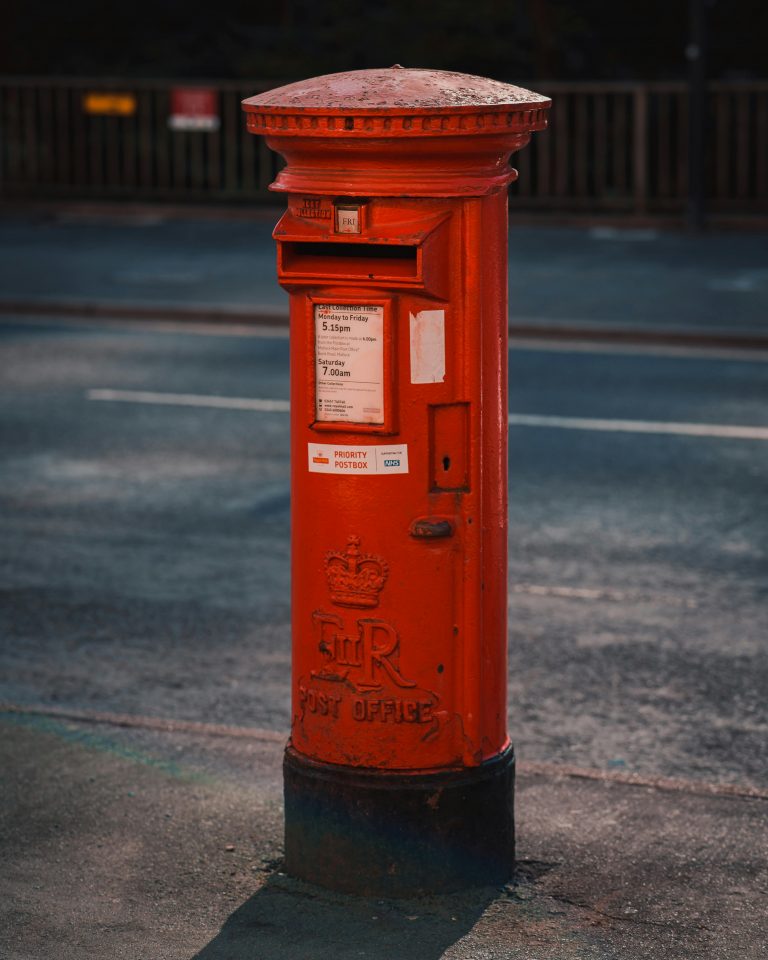 Iconic red British post box on a quiet urban street, captured in daylight.